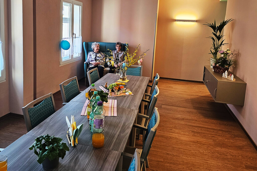 Raum mit langem Tisch und zwei &auml;lteren Frauen auf einem Sofa