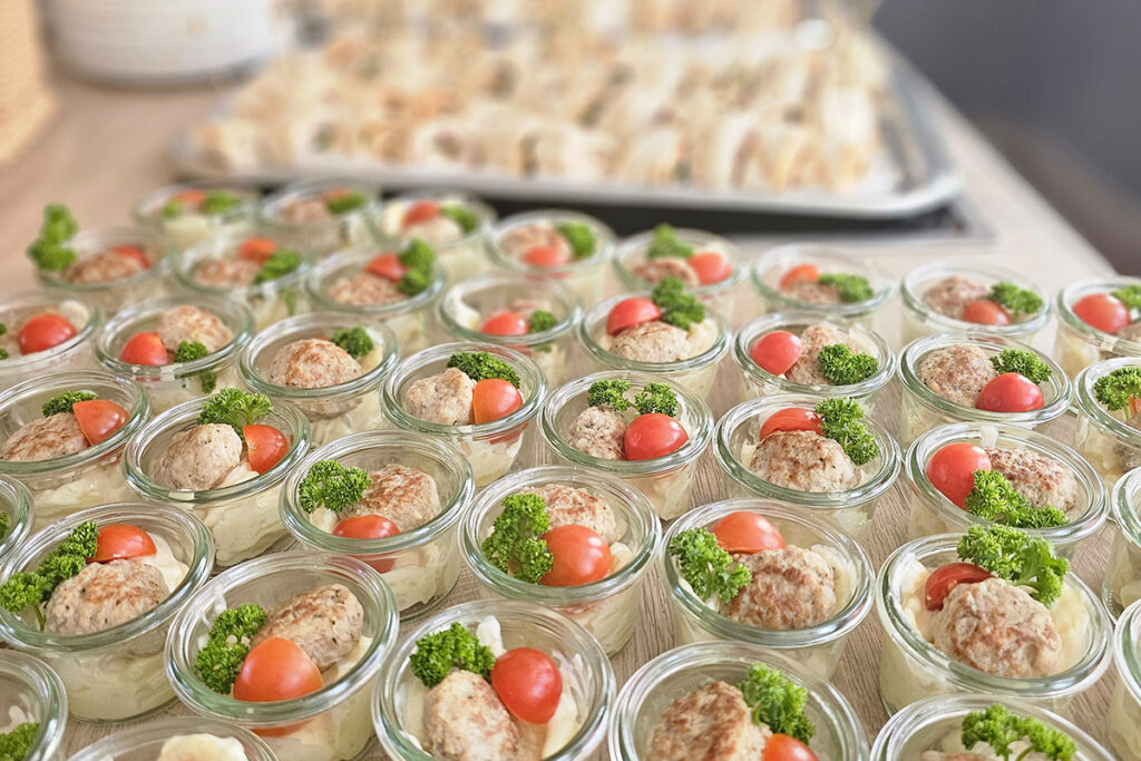 Kleine Gl&auml;ser mit einer Fleischspeise, Tomaten und Petersilie.