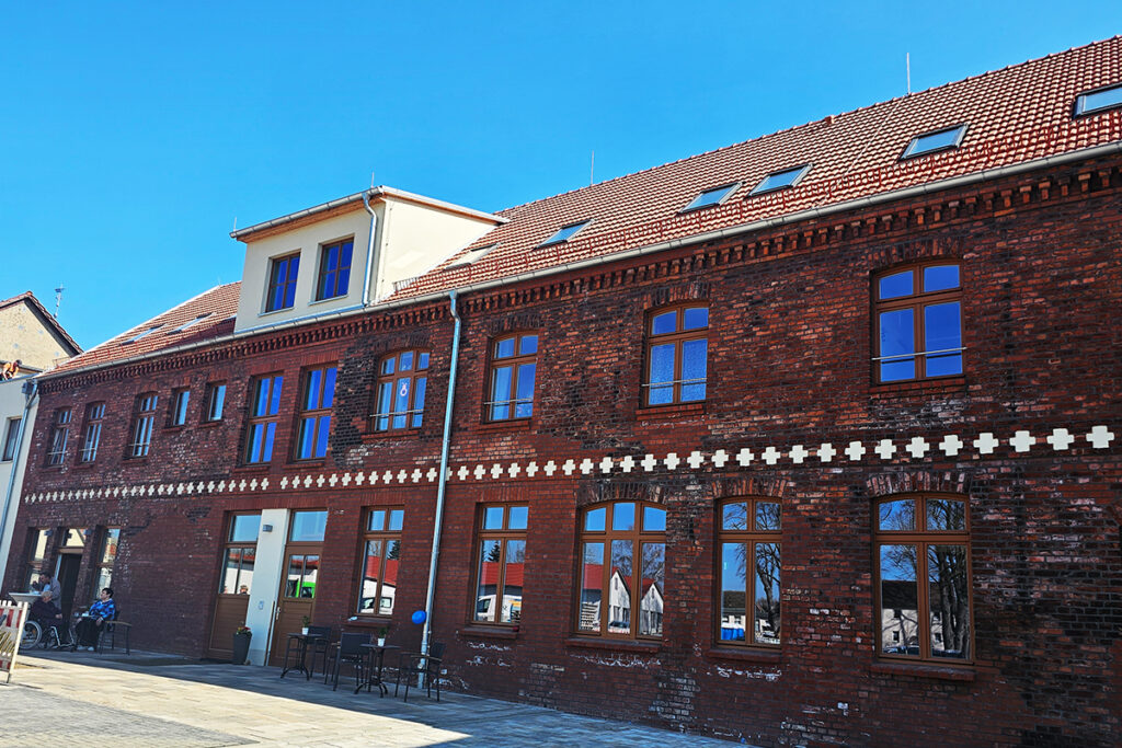 Backstein-Gebäude mit roten Ziegeln und Dachfenstern unter einem blauen Himmel.
