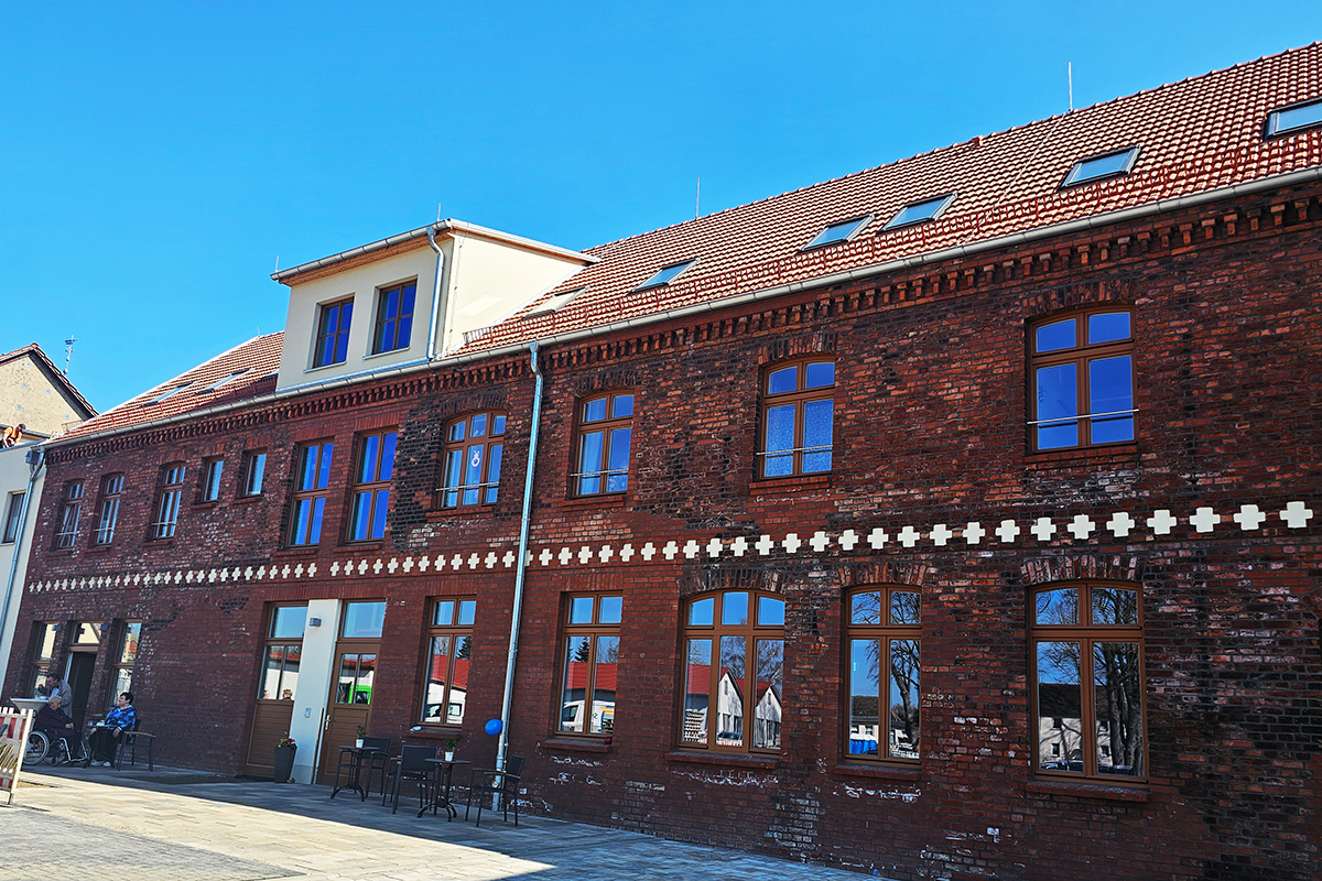 Backstein-Gebäude mit roten Ziegeln und Dachfenstern unter einem blauen Himmel.
