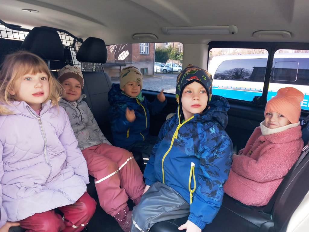 Fünf Kinder sitzen in einem Fahrzeug auf der Rückbank.