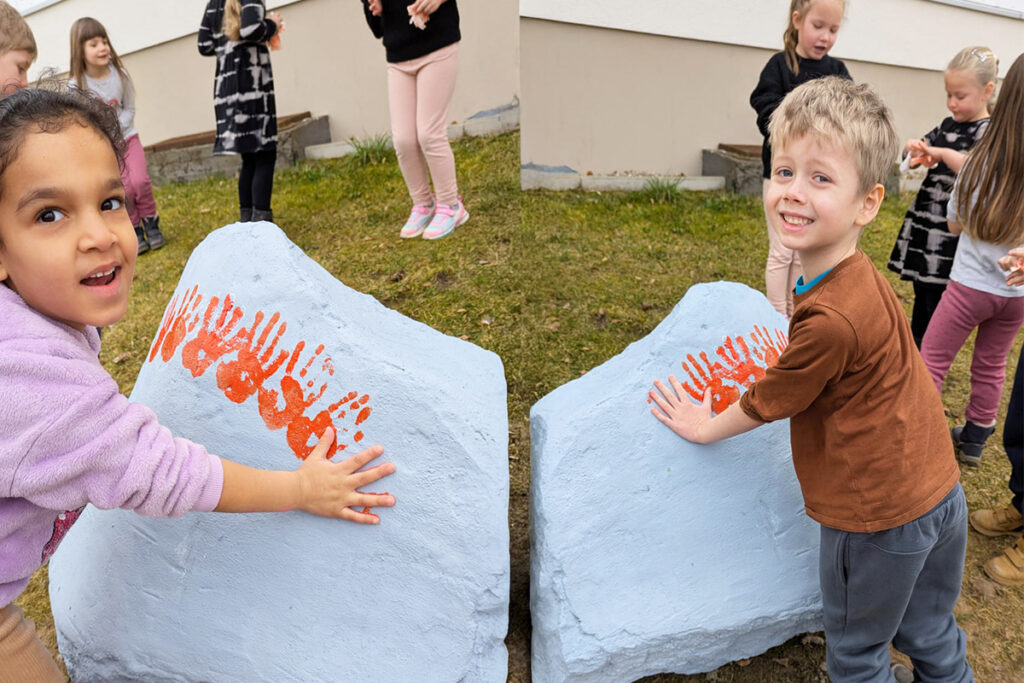 Kinder mit Handabdr&uuml;cken auf bemaltem Stein