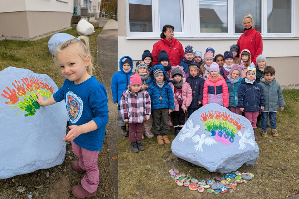 Gruppe von Kindern und Betreuerinnen vor bemaltem Stein.
