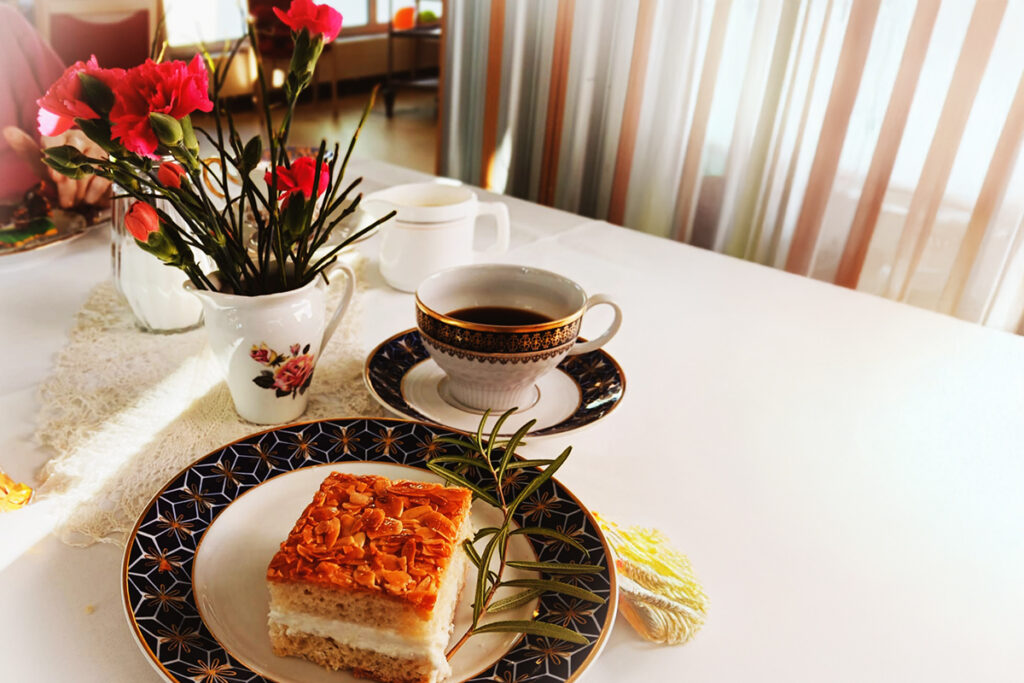 Kaffeetisch mit einer Torte, Kaffeetasse und Blumenstrau&szlig;