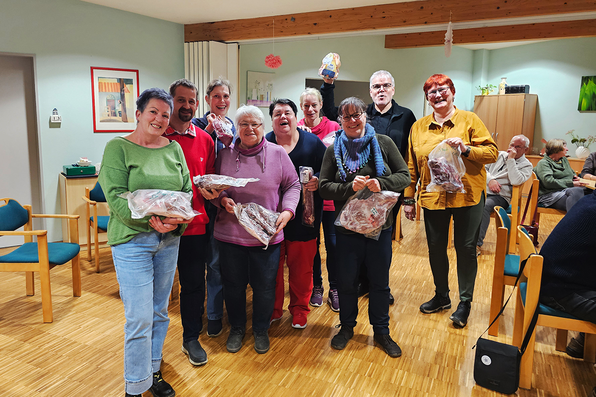 Gruppe von Menschen in einem Raum hält Päckchen in den Händen.