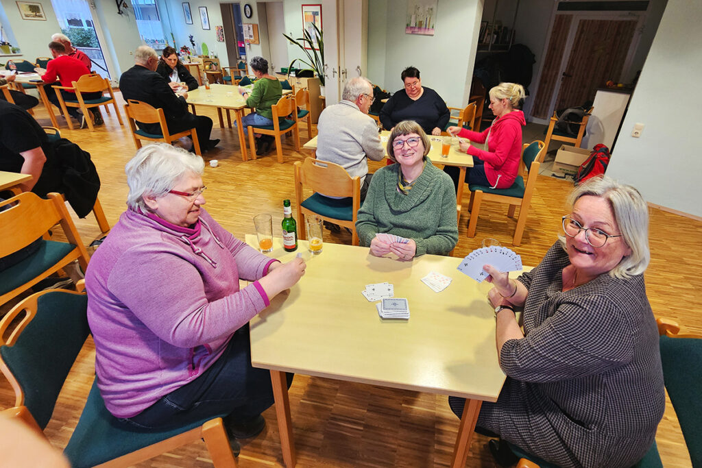 Menschen spielen Karten in einem Gemeinschaftsraum.