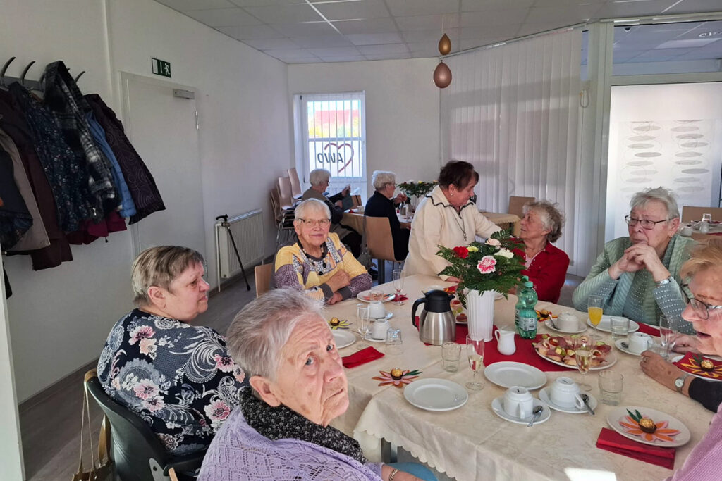 Seniorengruppe sitzt an einem gedeckten Tisch.