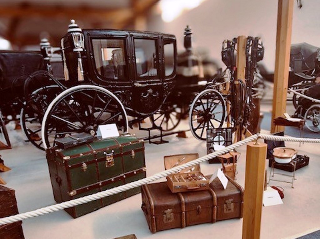 Historische schwarze Kutsche und Gepäckstücke in einem Museum