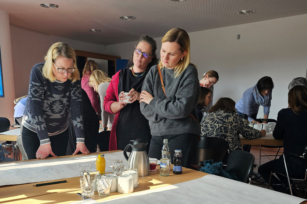 Gruppe von Frauen, die in einem Raum um einen Tisch herum arbeiten