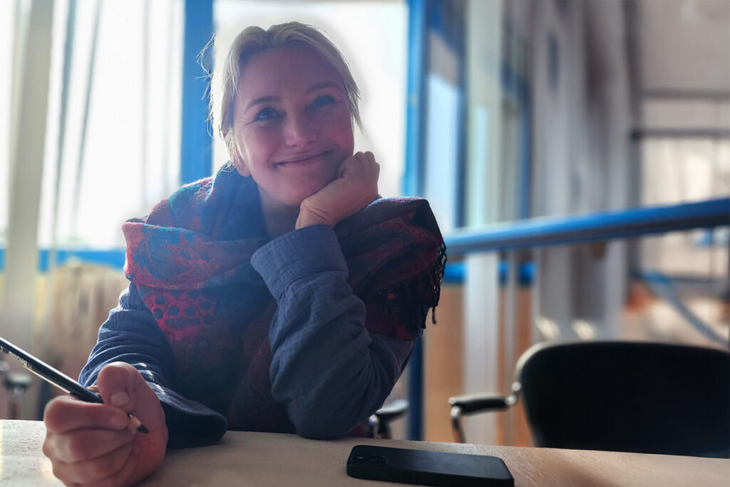 Frau in einem B&uuml;ro, die l&auml;chelnd am Tisch sitzt