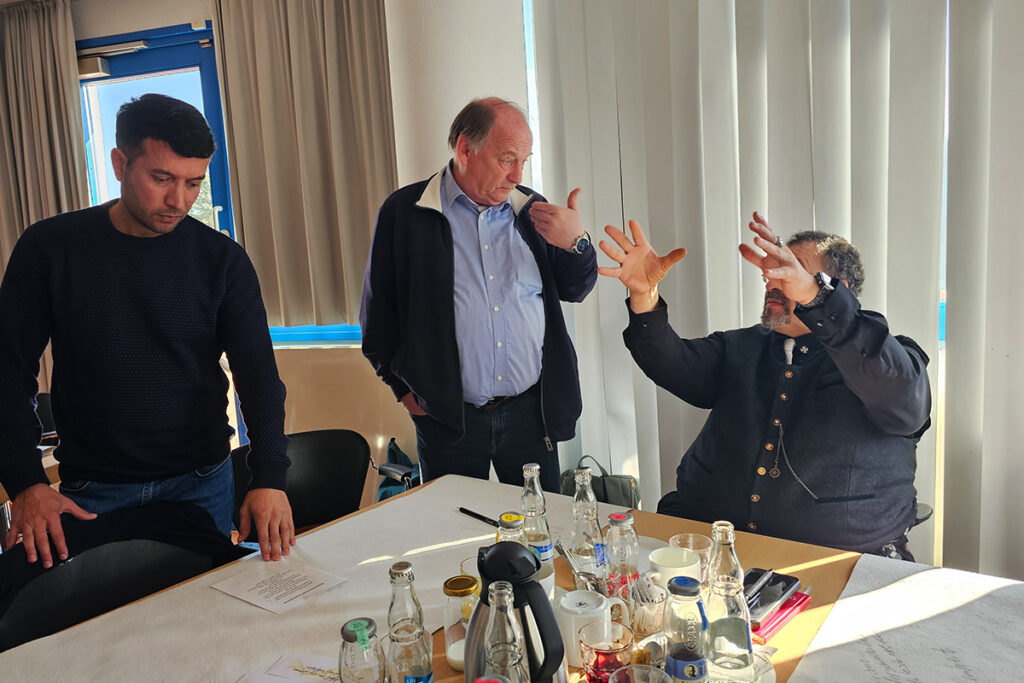 Drei Personen diskutieren an einem Tisch.