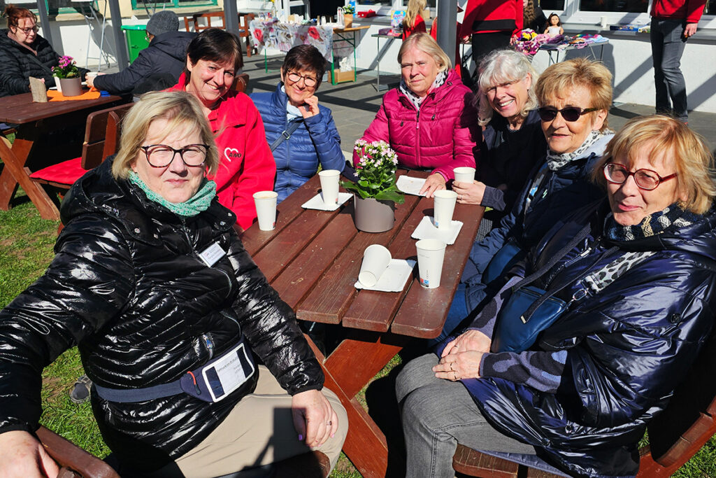 Eine Gruppe von Frauen sitzt an einem Holztisch im Freien.
