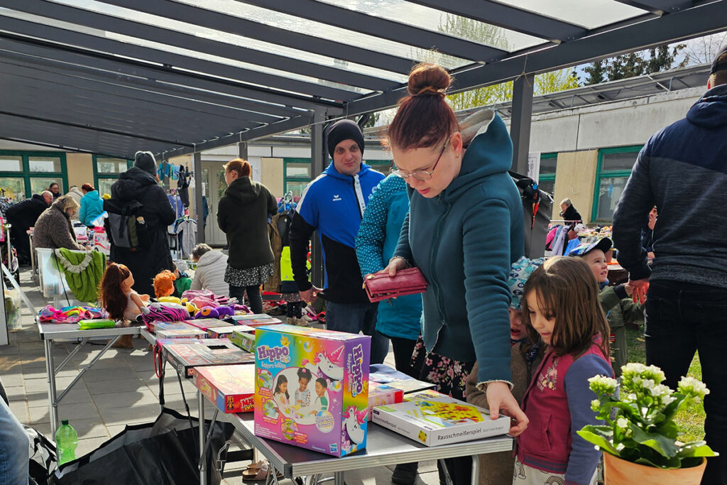 Menschen auf einem Flohmarkt, die sich Waren auf Tischen ansehen.