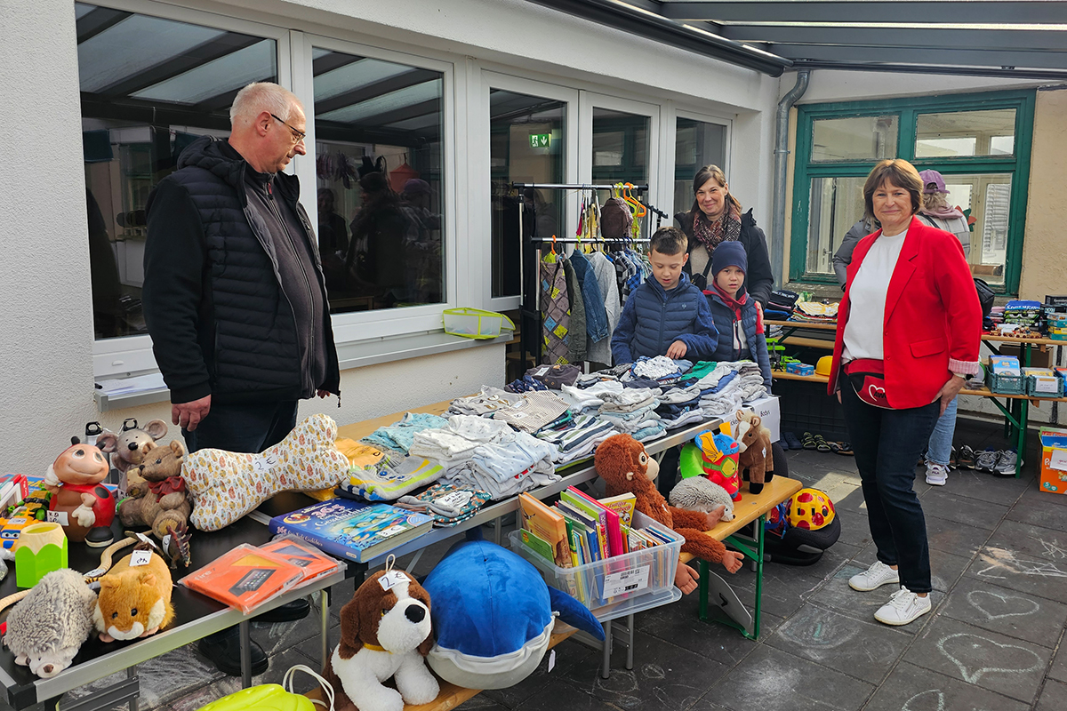 Flohmarktstand mit Menschen und Kindersachen