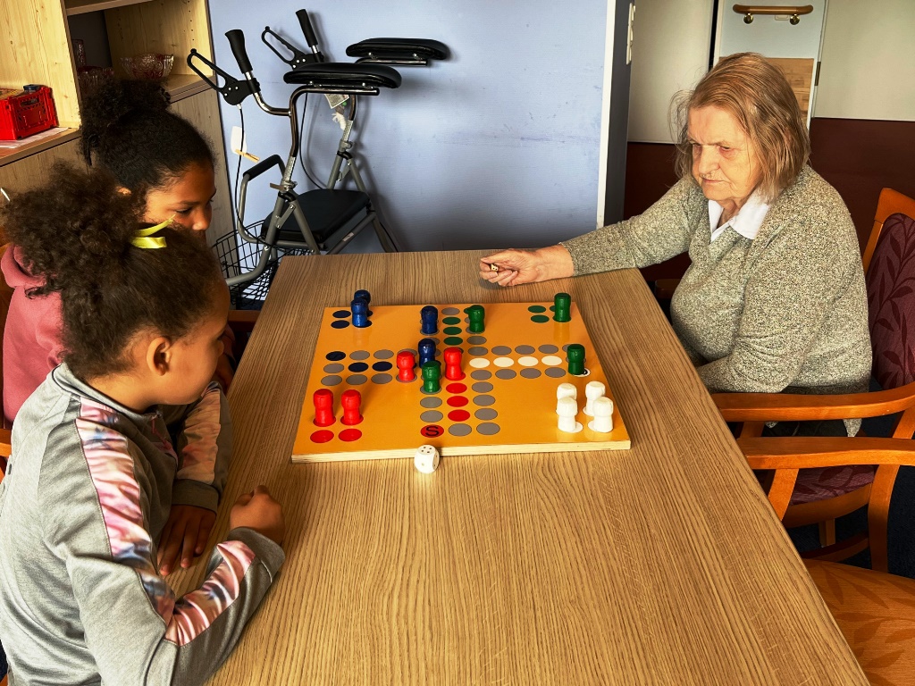 Drei Personen spielen ein Brettspiel an einem Tisch.