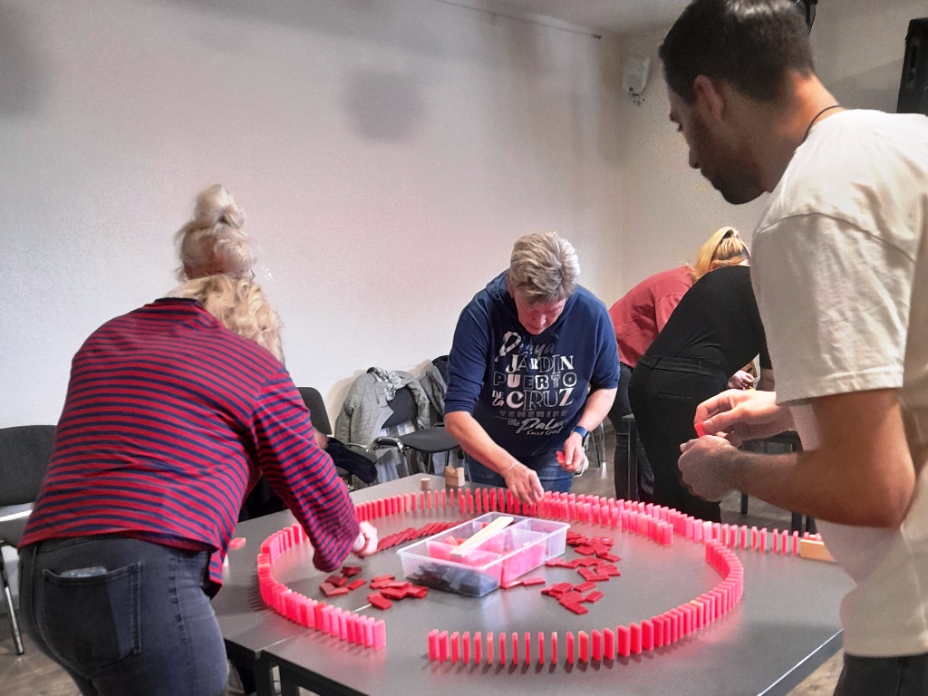 Gruppe von Menschen, die Dominosteine auf einem Tisch aufstellen