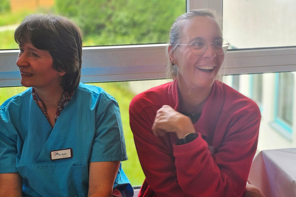 Zwei Frauen in einem Innenraum, l&auml;chelnd und in entspannter Atmosph&auml;re.