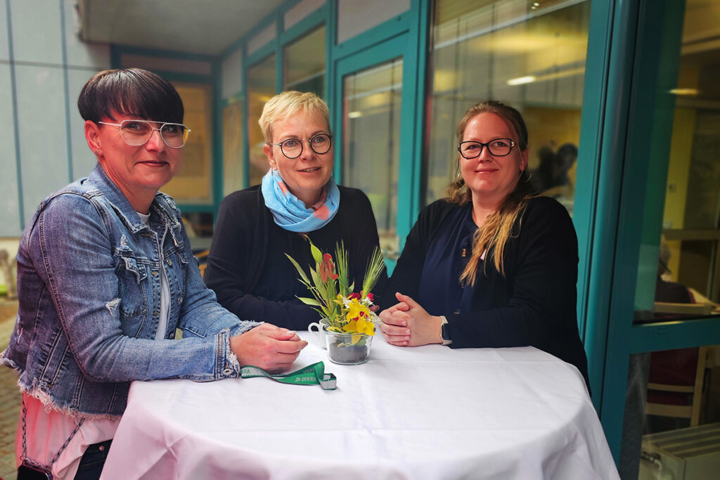 Drei Frauen an einem wei&szlig; gedeckten Stehtisch, mit Blumendekoration.