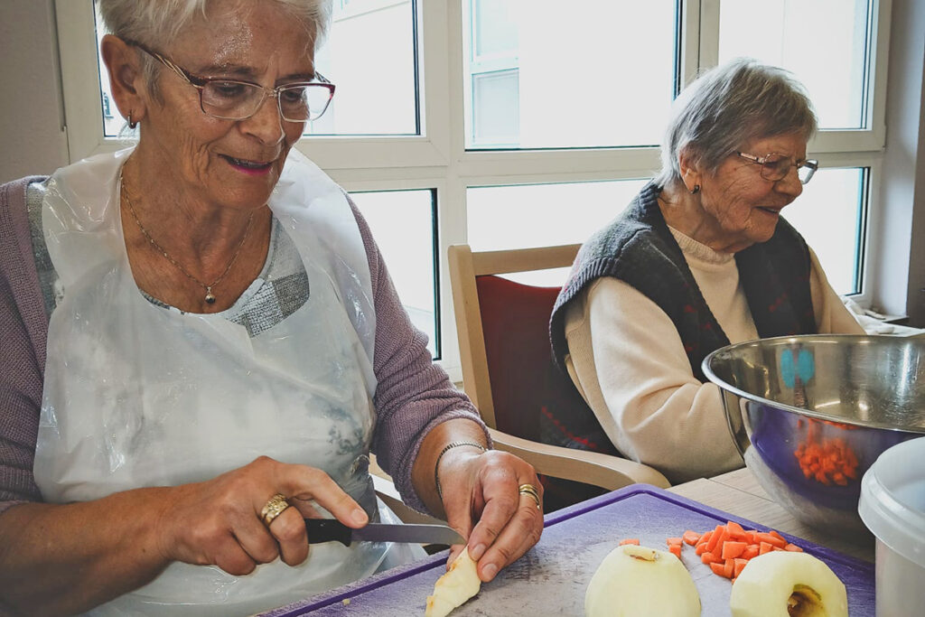 Zwei &auml;ltere Frauen beim gemeinsamen Kochen in einer K&uuml;che.