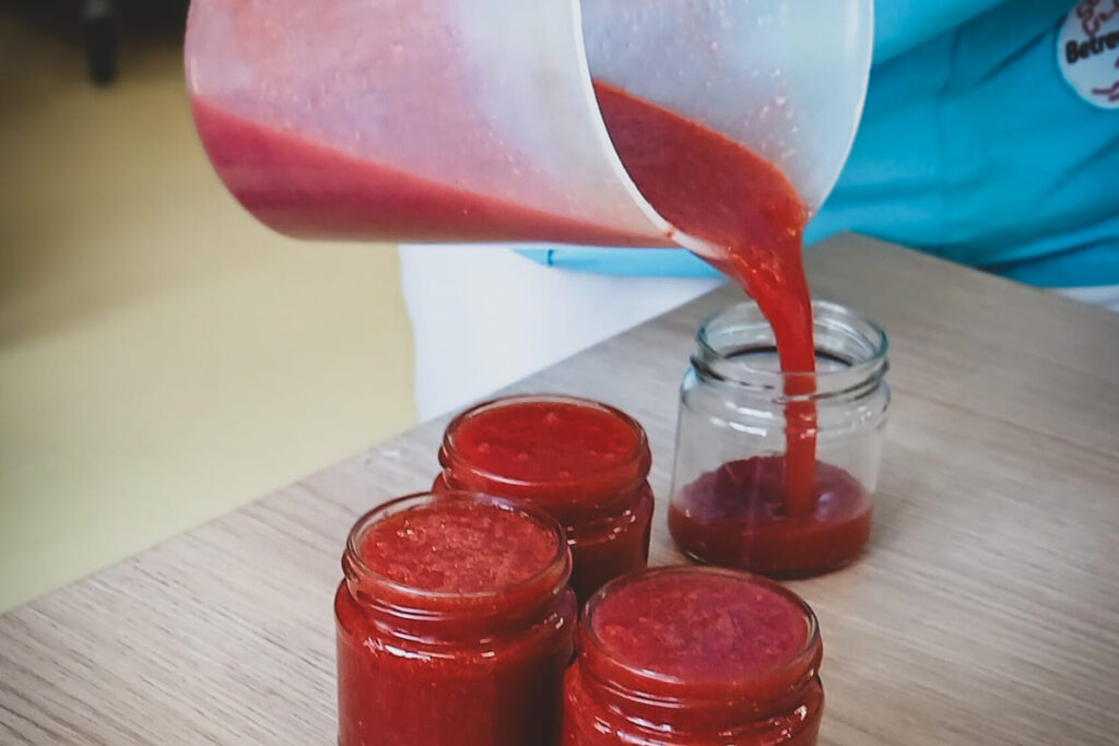 Eine Person f&uuml;llt rote Fl&uuml;ssigkeit in Gl&auml;ser.