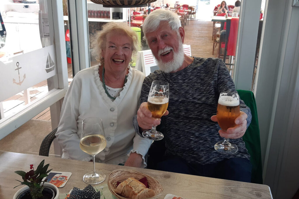 Lachendes &auml;lteres Paar mit Getr&auml;nken in einem Caf&eacute;