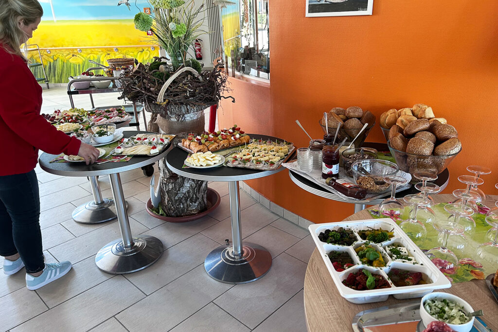 Buffet mit verschiedenen Speisen und einer Frau, die sich bedient.