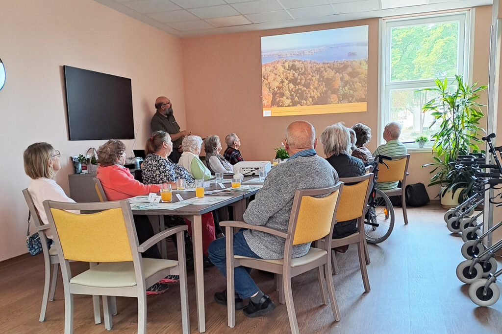 Ältere Menschen in einem Seminarraum, die einer Präsentation zuhören