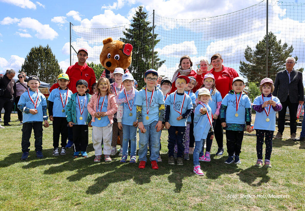 Eine Gruppe von Kindern und Erwachsenen auf einem Sportfeld