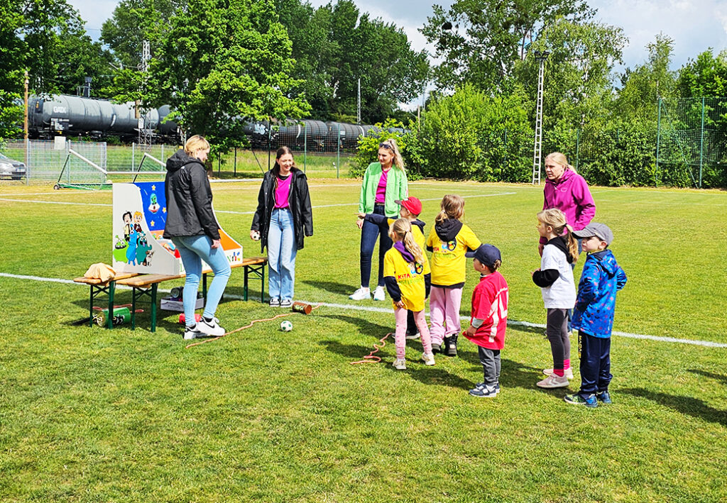 Kinder spielen auf einem Fu&szlig;ballfeld mit Betreuern
