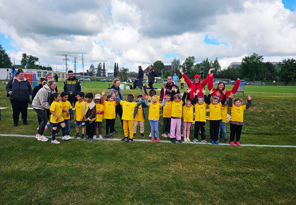 Gruppe Kinder mit Erwachsenen auf Fu&szlig;ballfeld