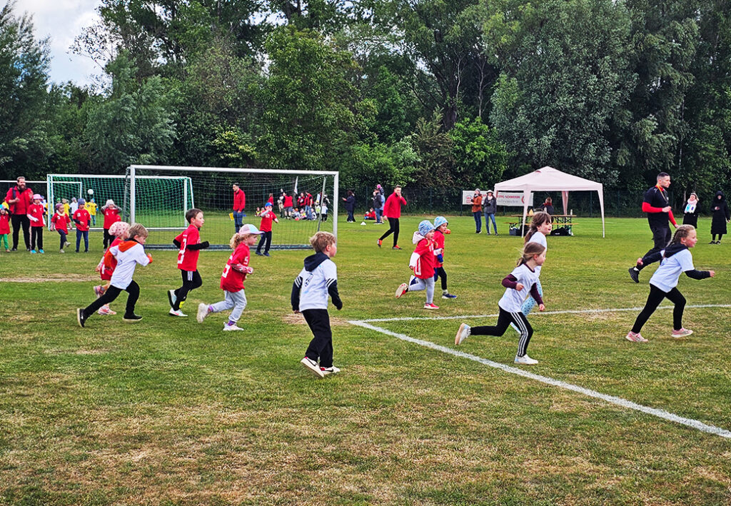 Eine Gruppe von Kindern, die auf einem Fu&szlig;ballplatz laufen.