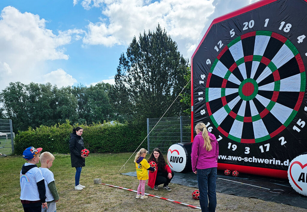 Menschen spielen Dart mit einem gro&szlig;en aufblasbaren Dartboard.