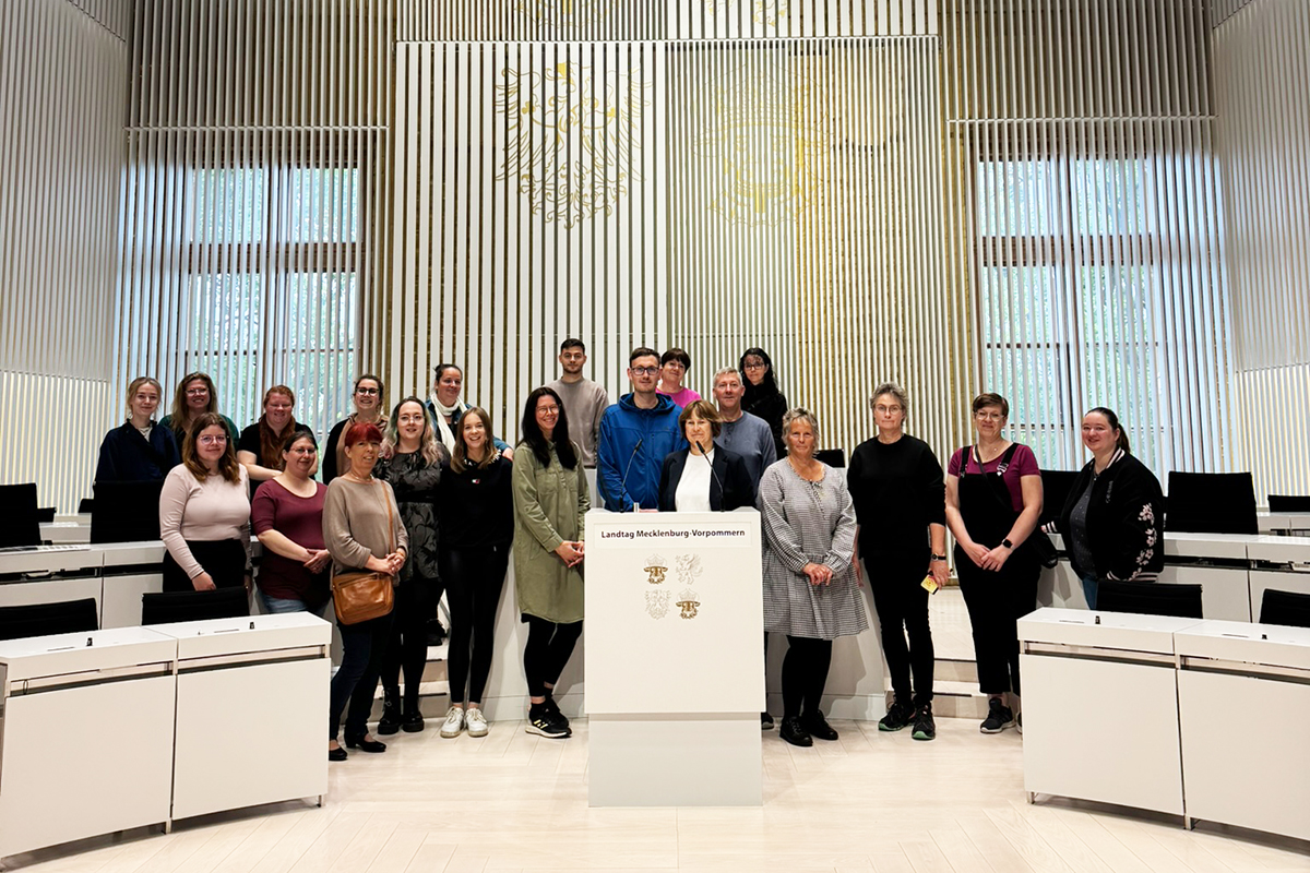 Gruppe von Menschen im Landtag von Mecklenburg-Vorpommern mit Pult im Vordergrund