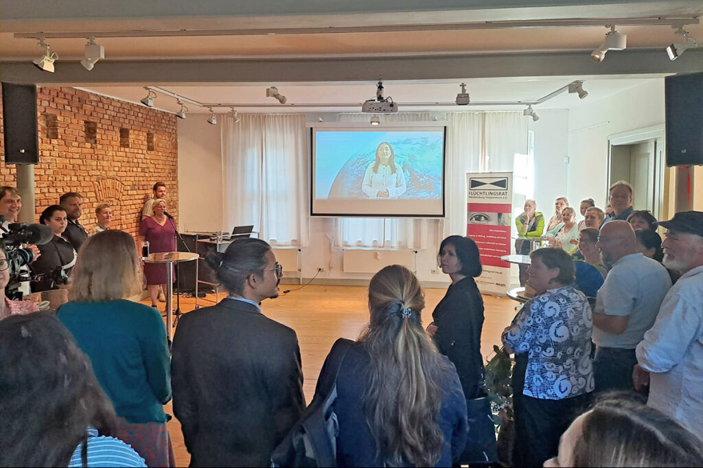 Menschenmenge bei einer Pr&auml;sentation in einem Raum mit Backsteinwand