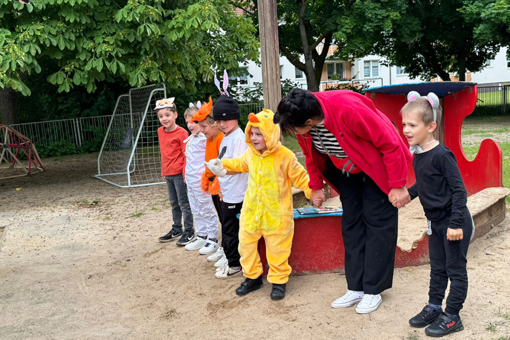 Kinder in Tierkost&uuml;men und eine Erwachsene auf einem Spielplatz