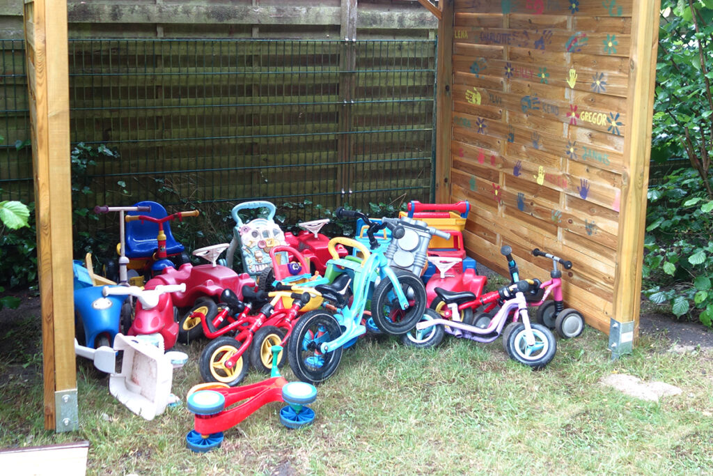 Kinderfahrzeuge in einem Holzunterstand