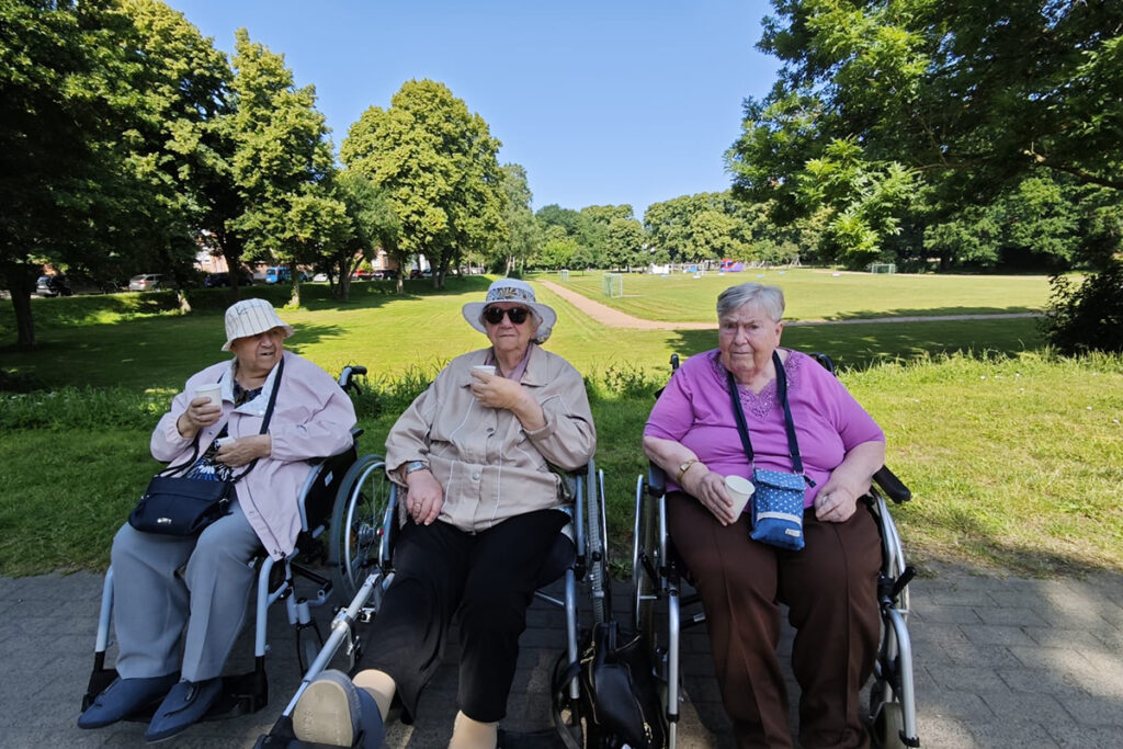 Drei &auml;ltere Frauen im Park auf Rollst&uuml;hlen sitzend.