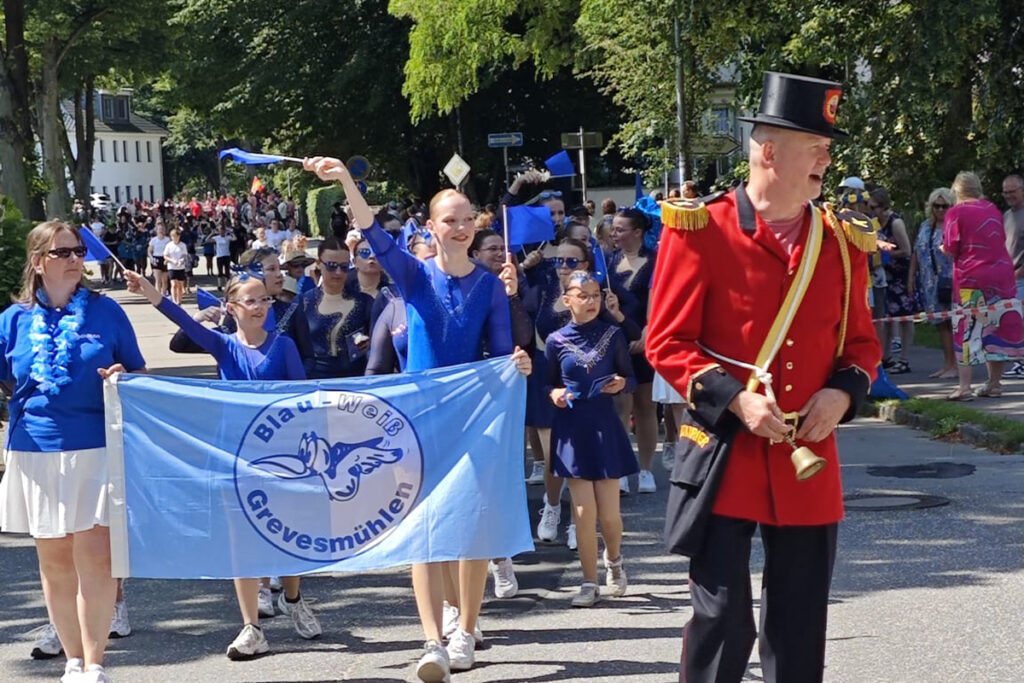 Parade mit Teilnehmern in blauen Uniformen und einer Person in roter Uniform