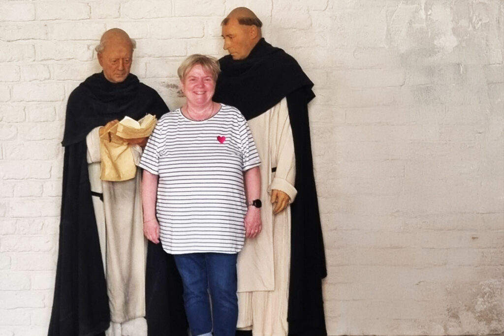 Eine Frau steht zwischen zwei Statuen von M&ouml;nchen in Roben.