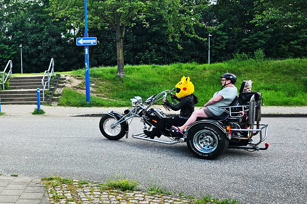 Motorradfahrer mit Pikachu-Helm und Beifahrer auf Straßenkreuzung