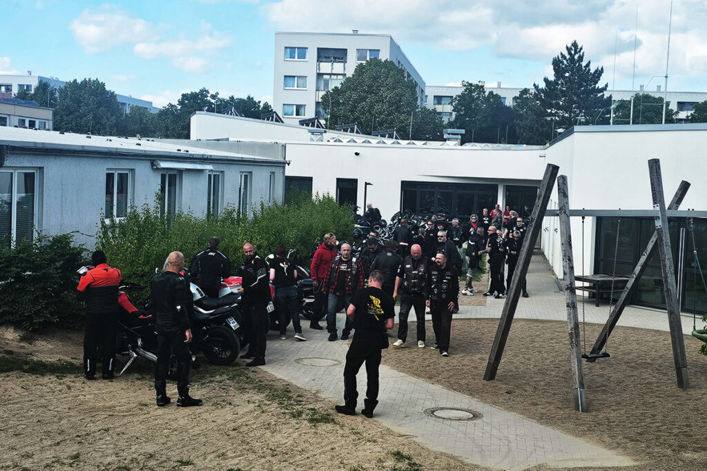 Gruppe von Motorradfahrern steht vor einem Geb&auml;ude