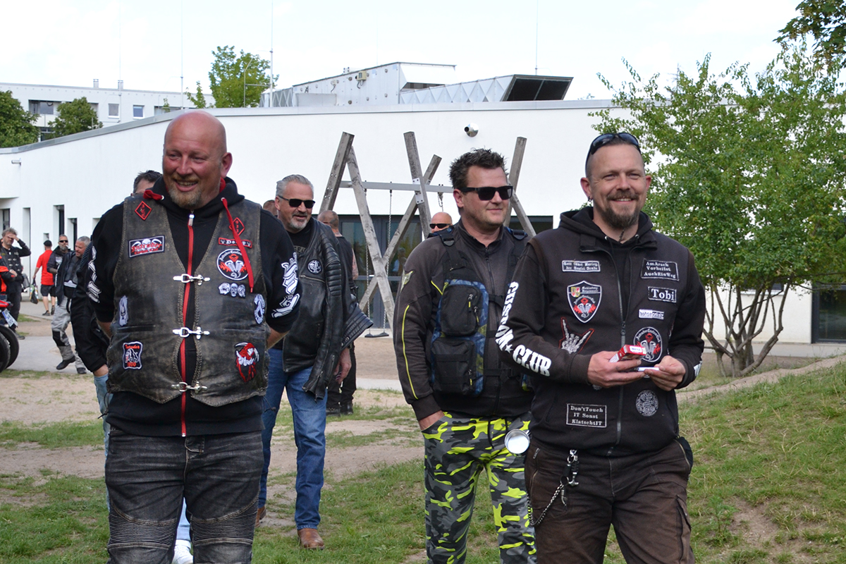 Viele Männer in Motorradkleidung lächeln in die Kamera.