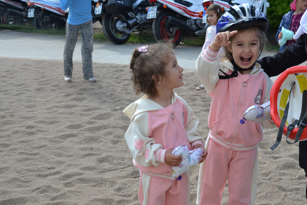 Zwei Kinder in rosa Anz&uuml;gen, eines tr&auml;gt einen Fahrradhelm.