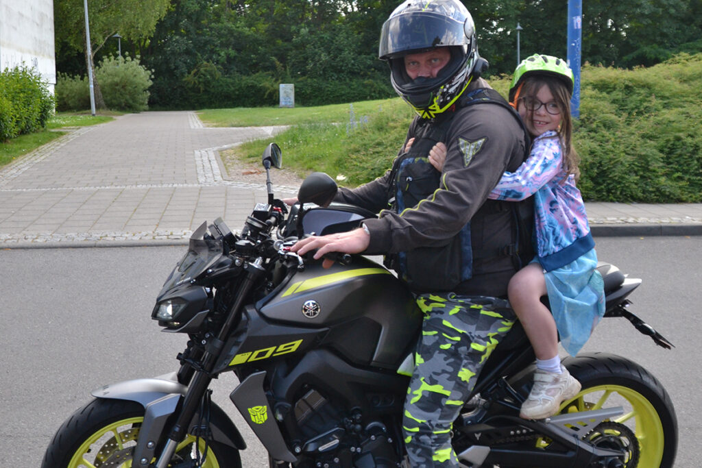 Eine Person auf einem Motorrad mit einem Kind als Beifahrer.