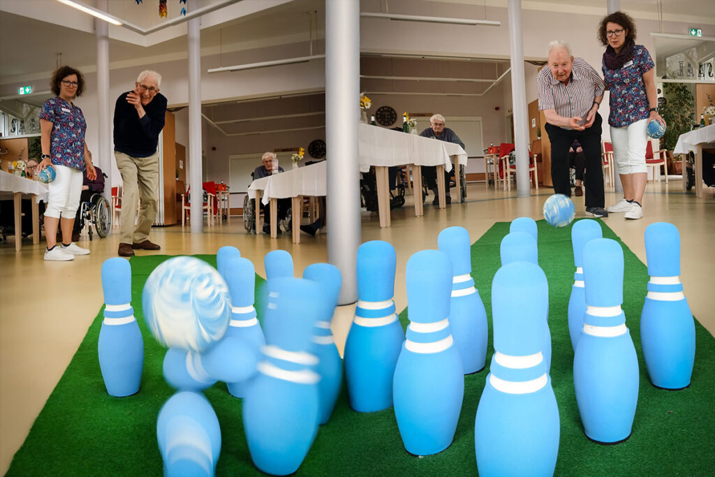 Menschen spielen Indoor-Kegeln in einem Gemeinschaftsraum.