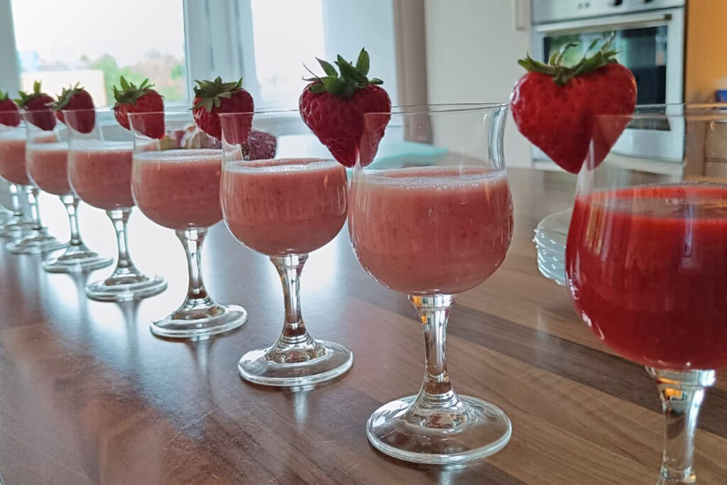 Reihe von mit Erdbeerpudding gef&uuml;llten Gl&auml;sern auf einem Tisch