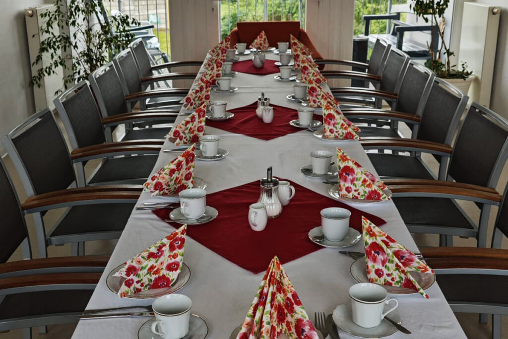 Ein lang gedeckter Tisch mit Geschirr und Servietten.