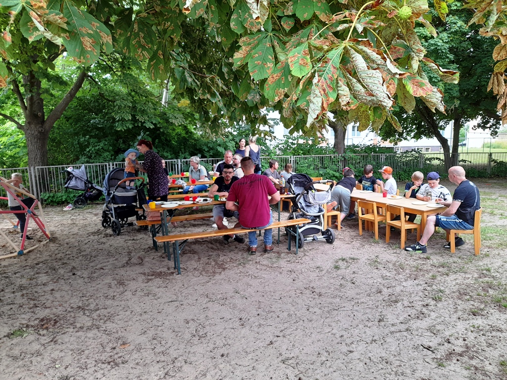 Menschen bei einer Outdoor-Veranstaltung unter einem Baum.