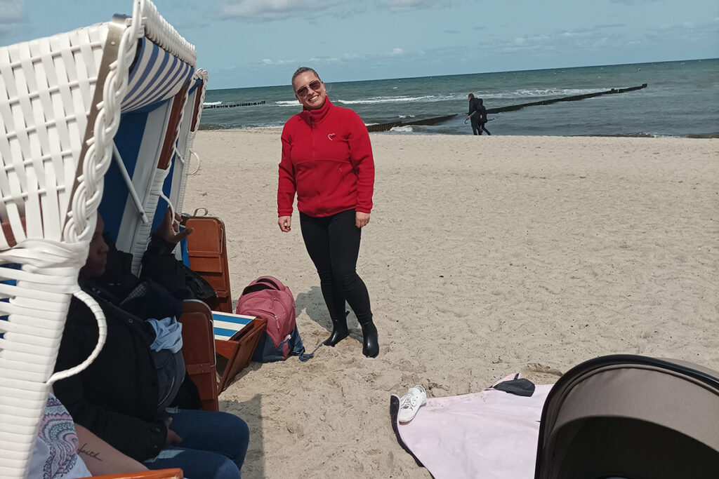 Personen am Strand mit Strandkorb und Meer im Hintergrund.