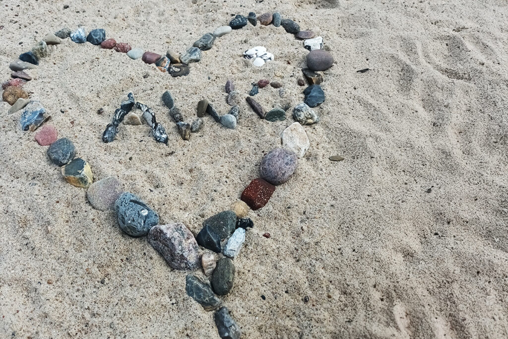 Steine in Herzform mit Schriftzug 'AWO' im Sand